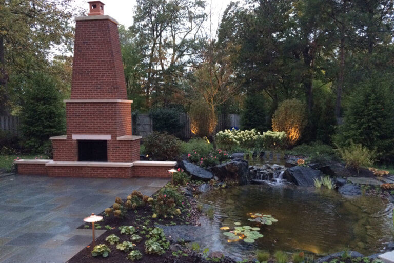 outdoor brick fireplace and backyard pond of the Haven Home in Wheaton, IL